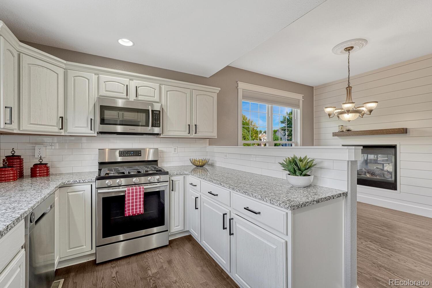 6335 Trailhead Road Highlands Ranch, CO 80130 - Photo 13 of 50 a kitchen with stainless steel appliances granite countertop a stove a sink and a wooden floor