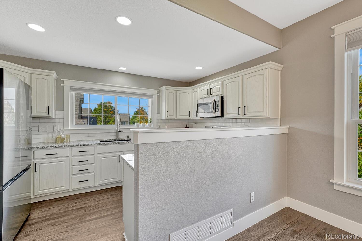 6335 Trailhead Road Highlands Ranch, CO 80130 - Photo 9 of 50 a kitchen with white cabinets stainless steel appliances a sink and a window
