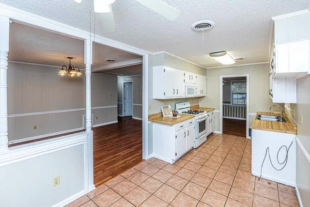 a large white kitchen with a stove a refrigerator a sink and dishwasher with a dining table