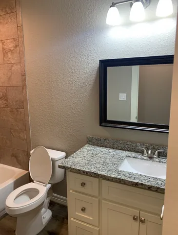 a bathroom with a granite countertop toilet sink and mirror