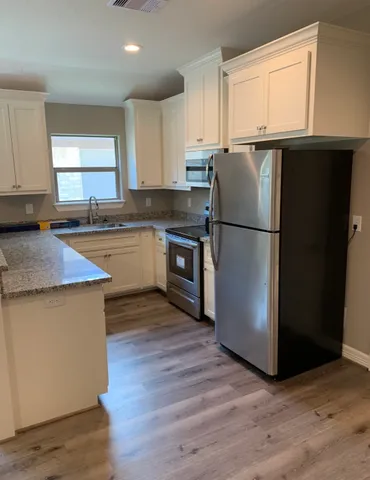 a kitchen with a refrigerator a microwave a sink and cabinets
