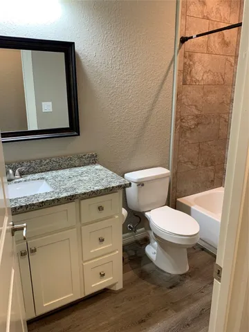 a bathroom with a granite countertop toilet sink and mirror