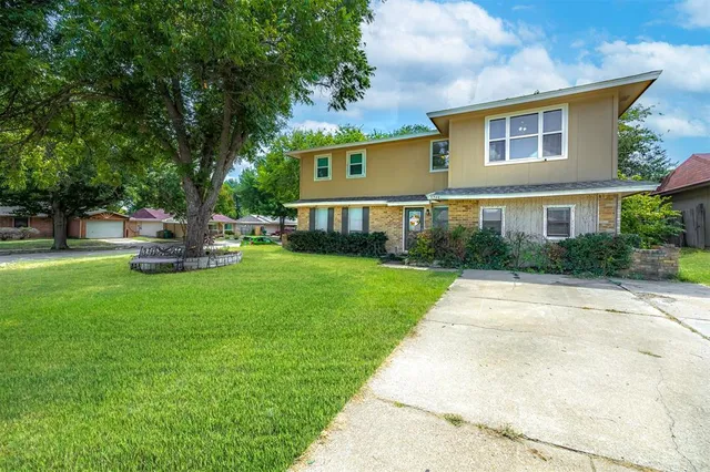 a front view of a house with a garden and trees