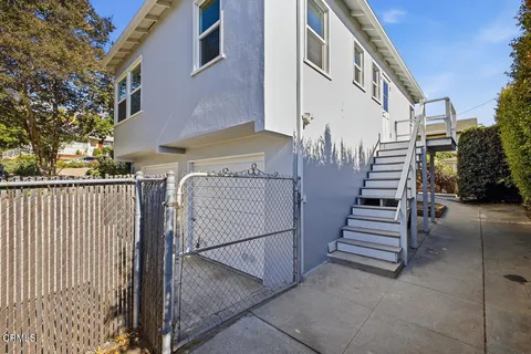 a view of a brick house with stairs and a small yard