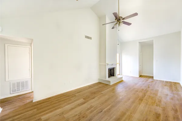 a view of a big room with wooden floor a ceiling fan and windows
