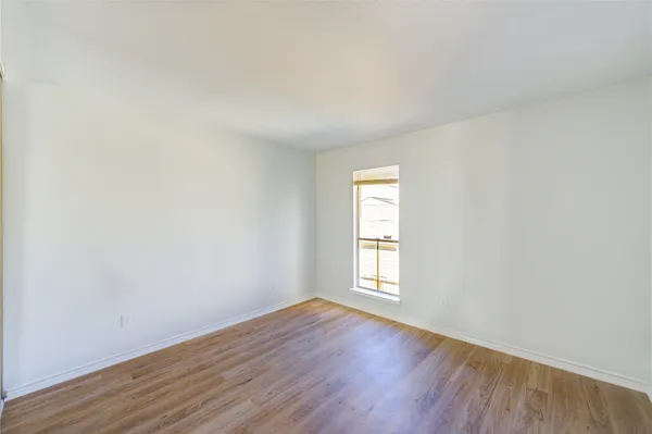 an empty room with wooden floor and window
