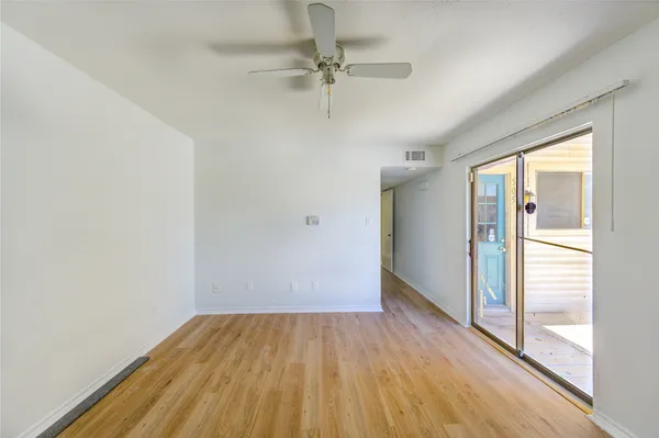 a view of a room with wooden floor a ceiling fan and windows