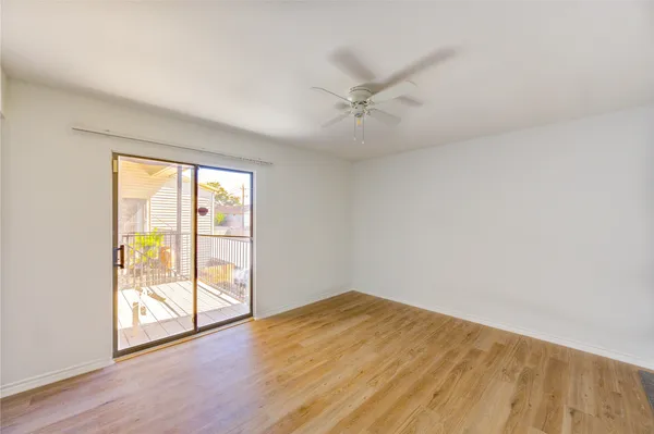 an empty room with wooden floor fan and windows