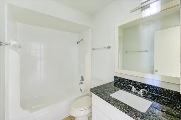 a bathroom with a granite countertop sink a toilet and shower