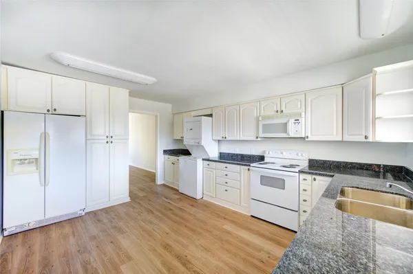 a large kitchen with cabinets wooden floor and stainless steel appliances