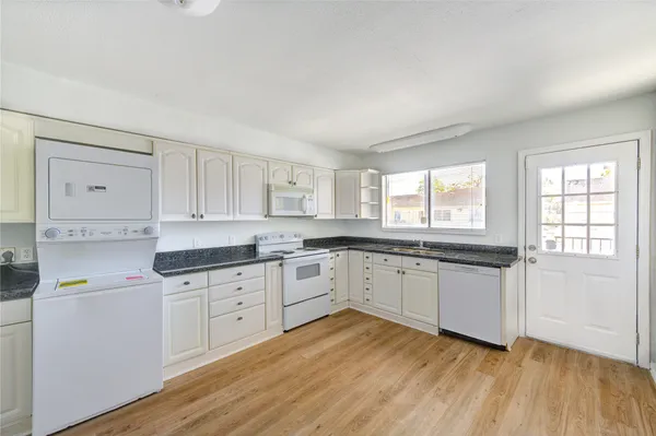 a kitchen with granite countertop white cabinets and white appliances