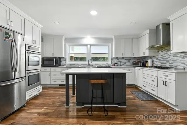 a kitchen with stainless steel appliances granite countertop a stove a sink a refrigerator a microwave and cabinets