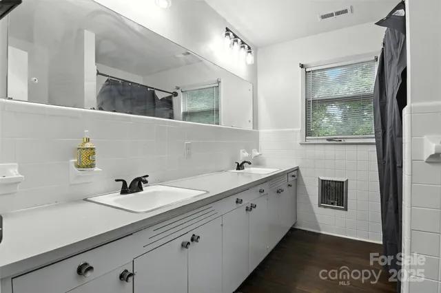 a bathroom with a double vanity sink mirror and bathtub