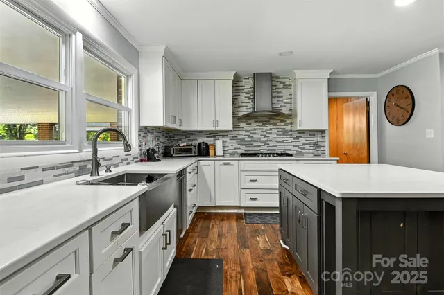 a kitchen with a sink dishwasher a stove and white cabinets with wooden floor
