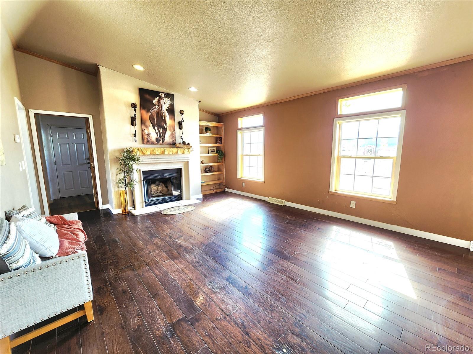 5339 County Road 19 Florence, CO 81226 - Photo 4 of 50 an empty room with windows a fireplace and wooden floor