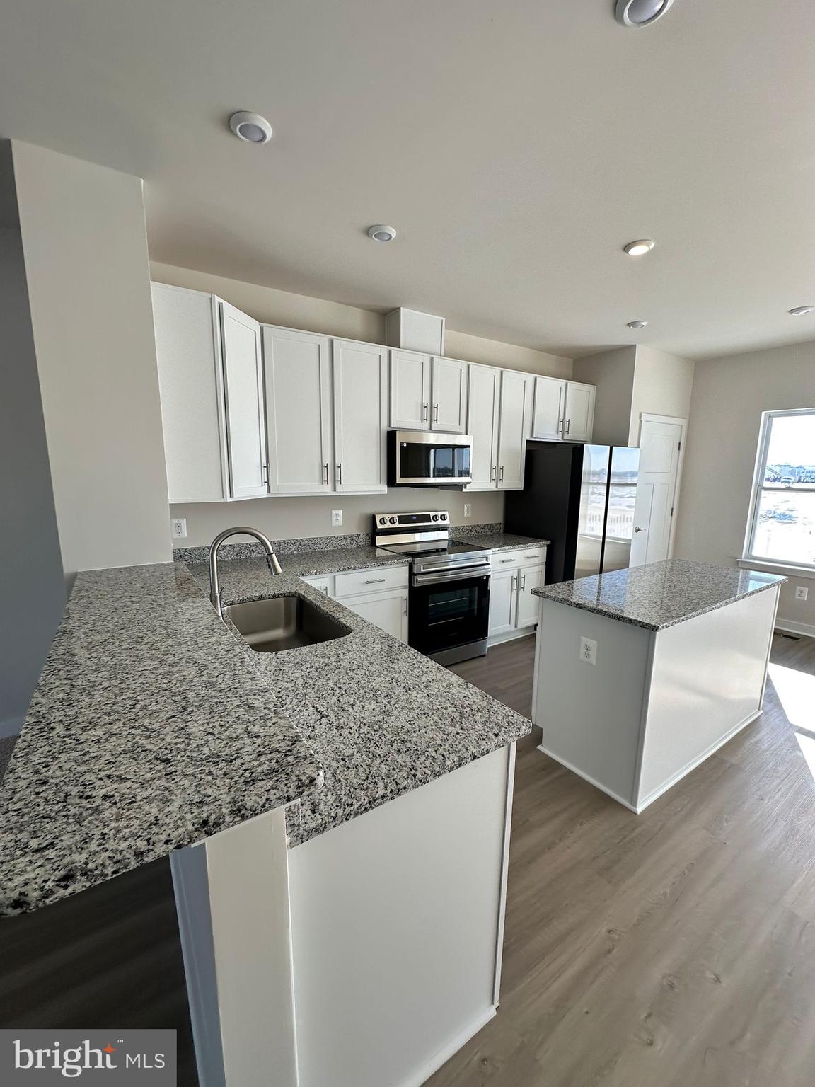 41 Sherman Avenue Ranson, WV 25438 - Photo 8 of 19 a kitchen with kitchen island granite countertop a stove top oven a sink a counter space and cabinets