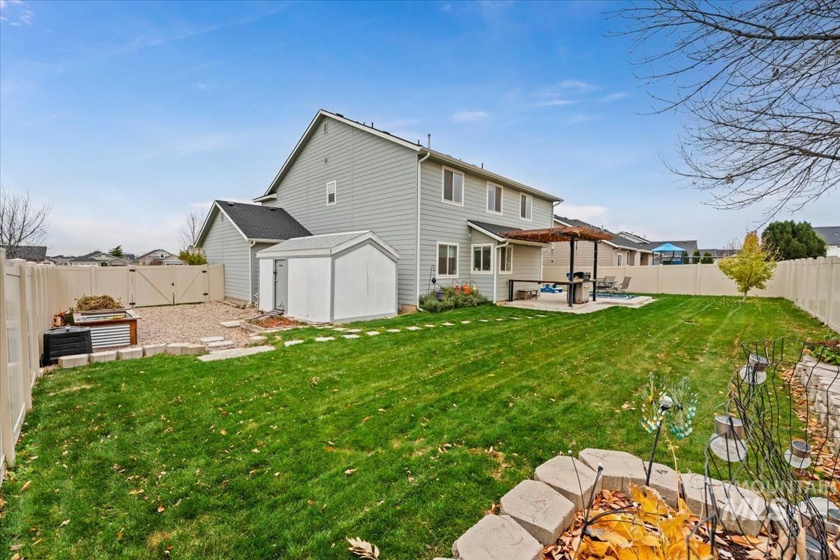 4585 West Everest Street Meridian, ID 83646 - Photo 33 of 37 Rear view of house featuring a fenced backyard, a patio, a pergola, and a garden