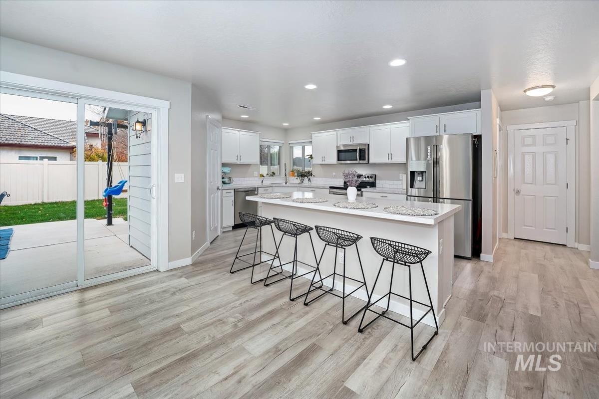 4585 West Everest Street Meridian, ID 83646 - Photo 10 of 37 Kitchen with appliances with stainless steel finishes, a breakfast bar, white cabinets, recessed lighting, and light wood-style floors