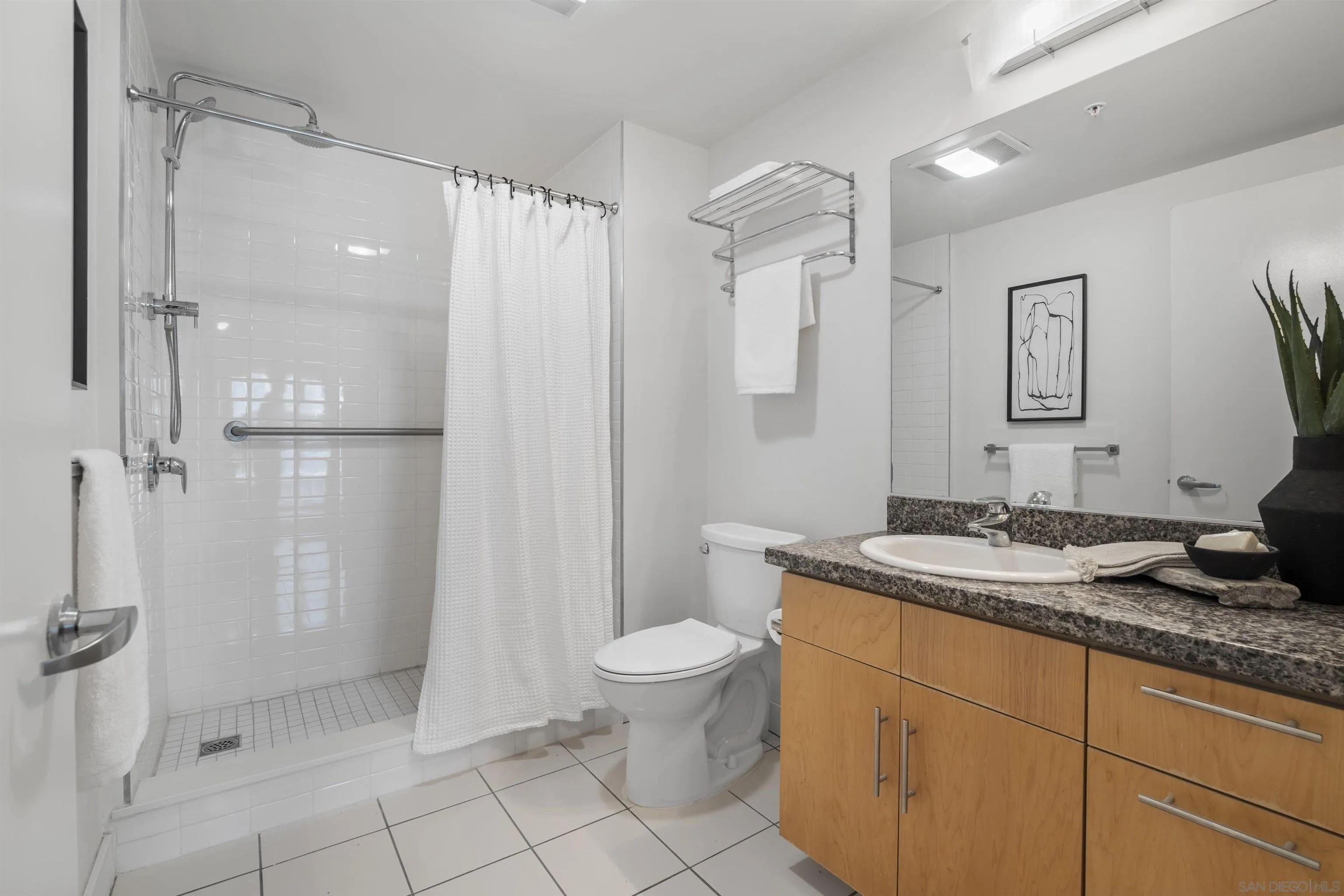 3812 Park Boulevard, Unit 412 San Diego, CA 92103 - Photo 11 of 24 a bathroom with a granite countertop sink a toilet and a shower