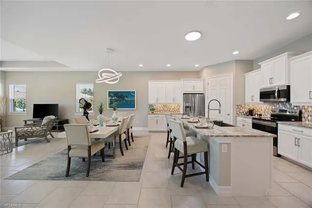 a kitchen with stainless steel appliances kitchen island granite countertop a sink a stove a dining table and chairs