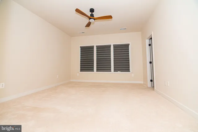 an empty room with a ceiling fan and window