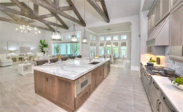 a large white kitchen with kitchen island a large counter space a sink stainless steel appliances and cabinets