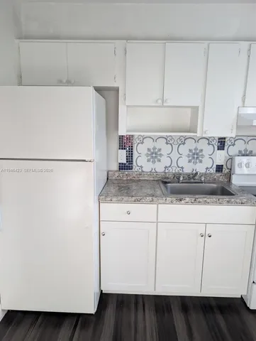 a kitchen with a refrigerator and white cabinets