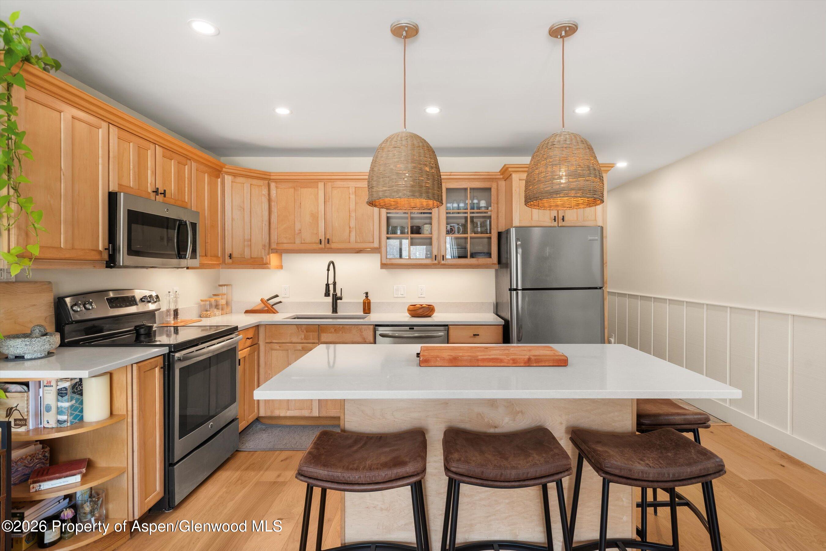 400 Wood Road, Unit D1206 Snowmass Village, CO 81615 - Photo 7 of 12 a kitchen with stainless steel appliances granite countertop a sink a stove a refrigerator cabinets and a dining table with wooden floor