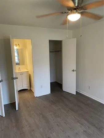 a view of a small space with wooden floor a ceiling fan and windows