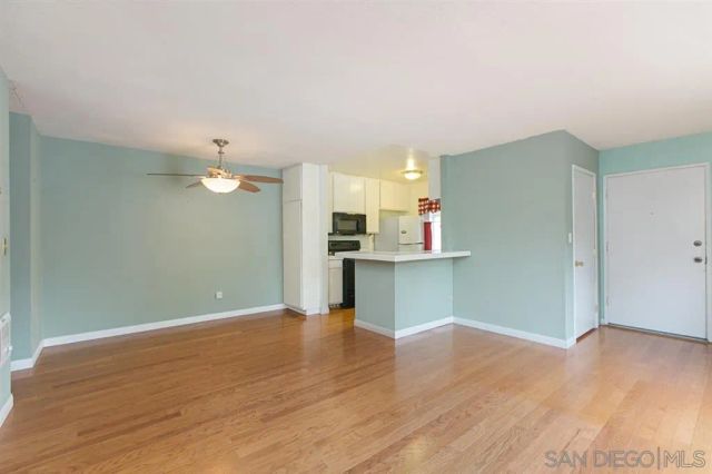 a view of an empty room with window and wooden floor