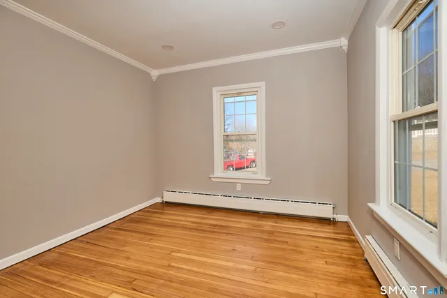 a view of empty room with wooden floor and fan