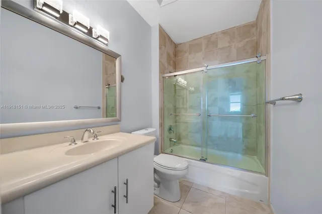 a bathroom with a shower sink vanity mirror and toilet