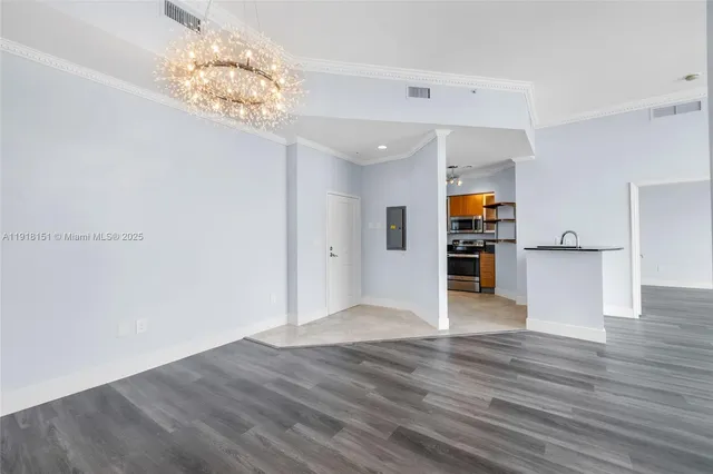 a view of empty room with wooden floor and kitchen