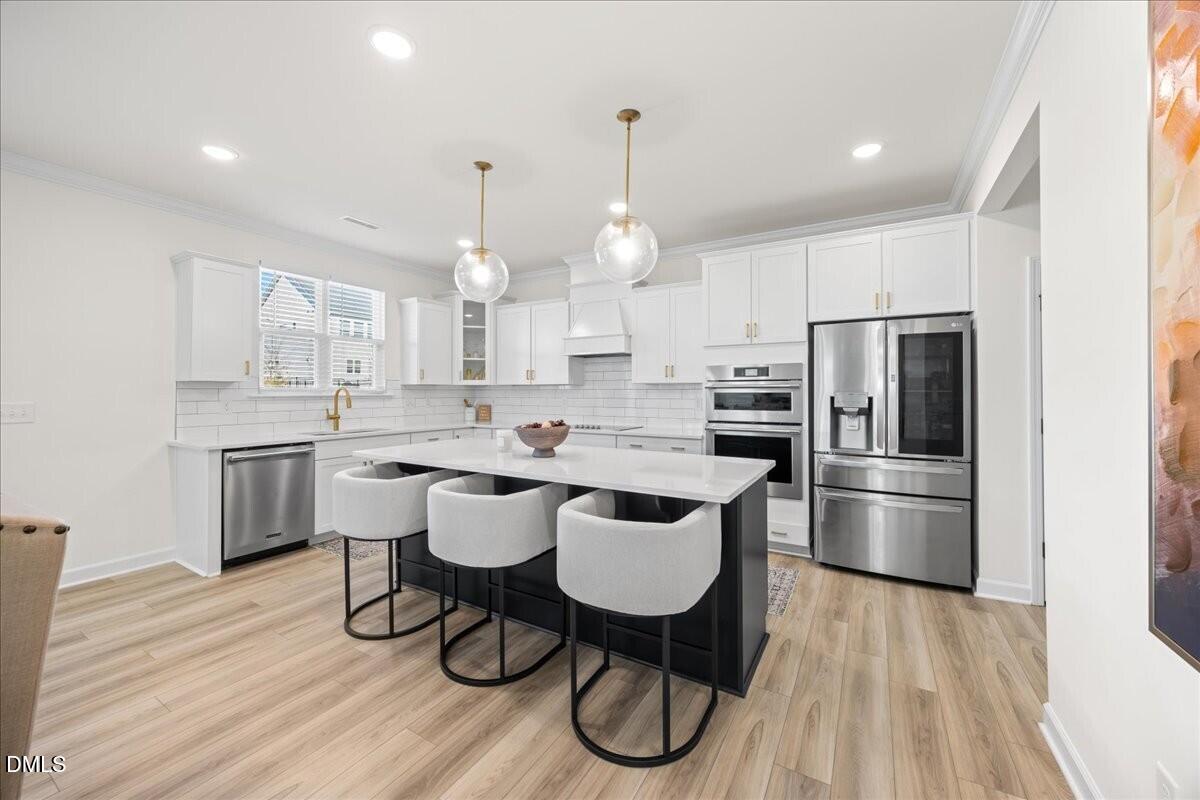 653 Craftsman Rdg Trail Knightdale, NC 27545 - Photo 15 of 50 a kitchen with stainless steel appliances a dining table chairs stove microwave and cabinets