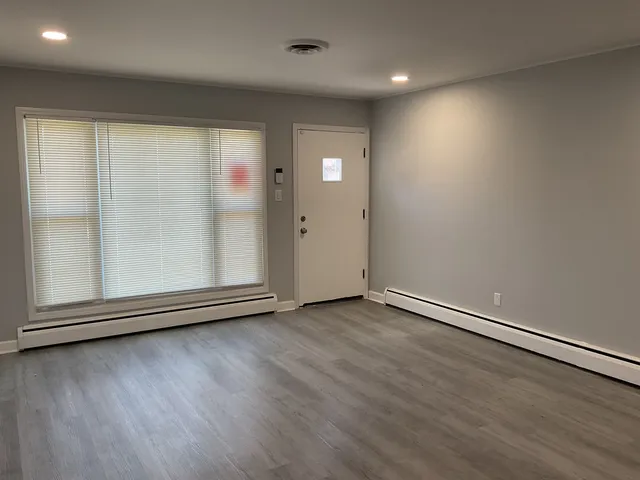 an empty room with wooden floor and windows with curtains
