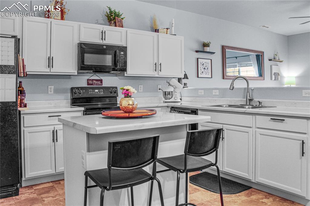 7649 Grand Fir Point Colorado Springs, CO 80908 - Photo 5 of 19 a kitchen with stainless steel appliances a stove a sink a microwave and white cabinets
