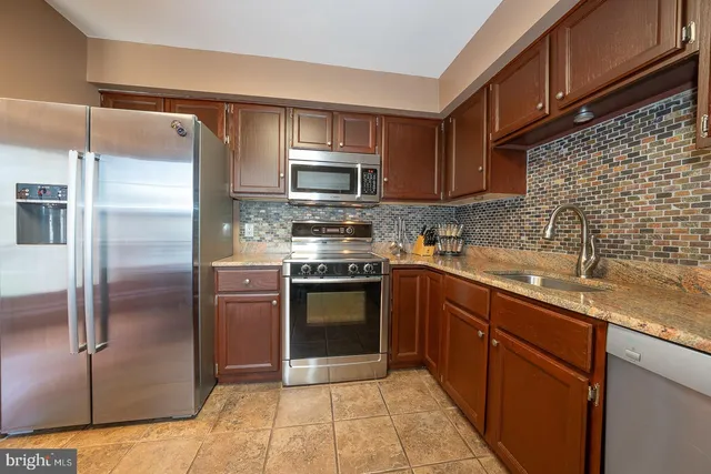a kitchen with stainless steel appliances granite countertop a refrigerator and a sink