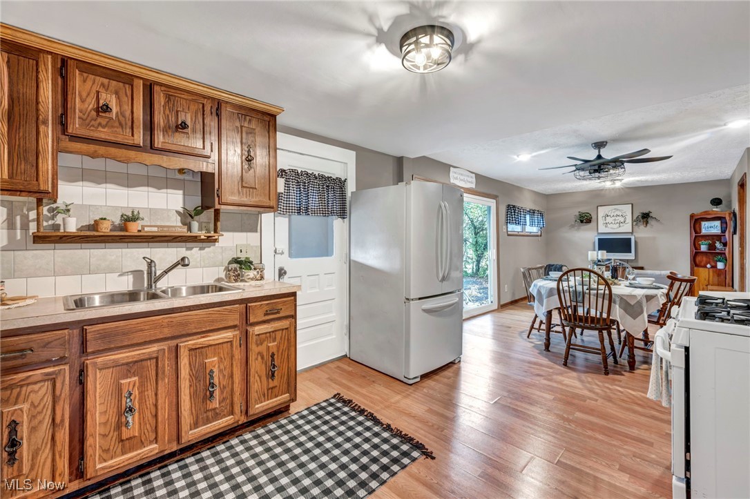 6030 Dunham Road Maple Heights, OH 44137 - Photo 19 of 50 Kitchen featuring white appliances, decorative backsplash, light countertops, light wood-style floors, and brown cabinetry