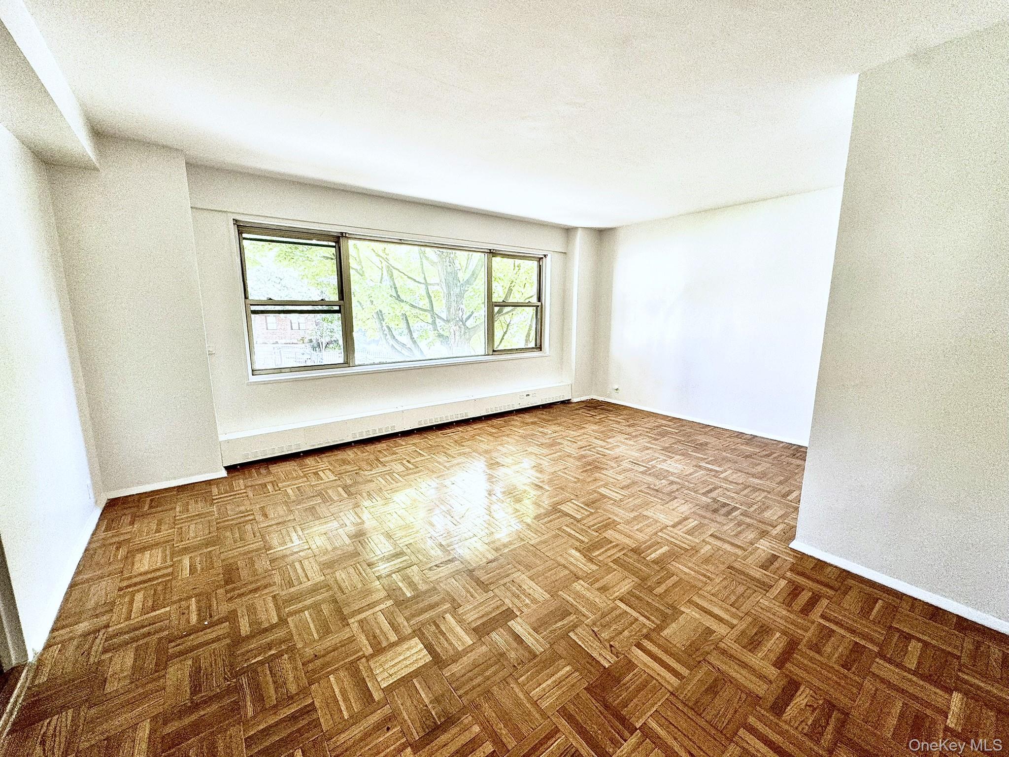9 Fordham Hill Ovl, Unit 1H Bronx, NY 10468 - Photo 12 of 21 an empty room with wooden floor and windows