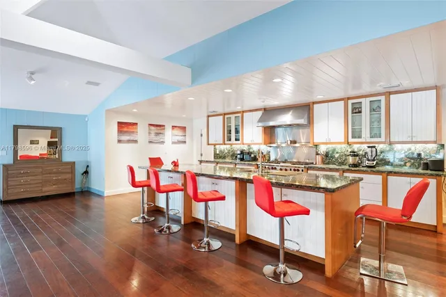 a view of a kitchen with granite countertop a dining table chairs sink and cabinets