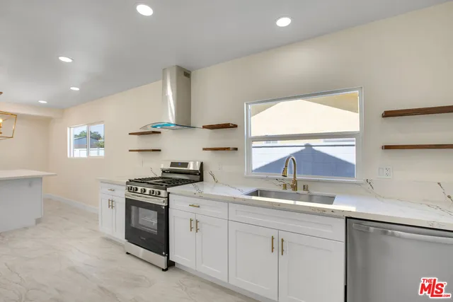 a kitchen with stainless steel appliances granite countertop a sink a stove and a window