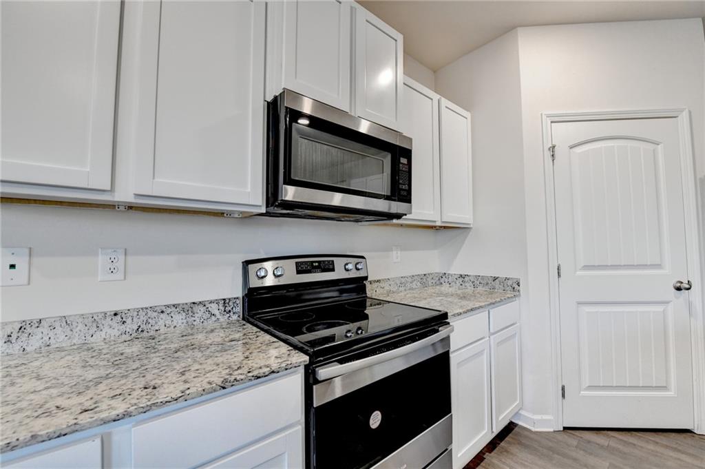 393 Walnut Grv Way Pendergrass, GA 30567 - Photo 11 of 45 a kitchen with stainless steel appliances granite countertop white cabinets and a stove