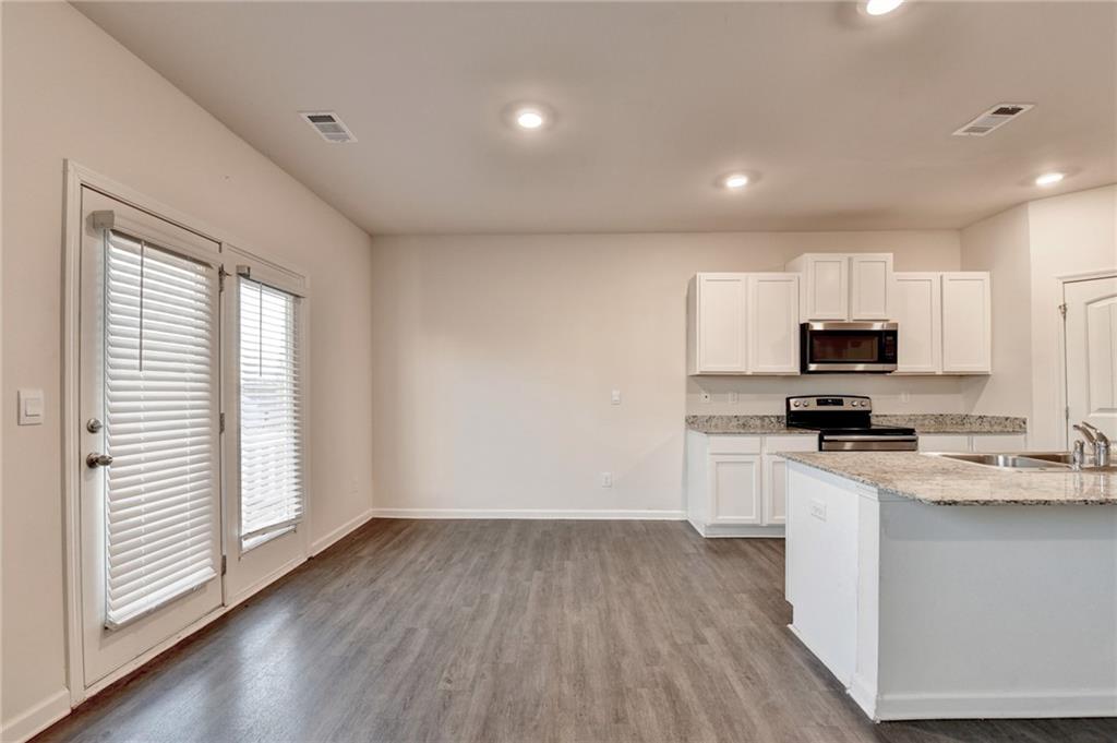 393 Walnut Grv Way Pendergrass, GA 30567 - Photo 14 of 45 a kitchen with granite countertop a stove top oven a sink a refrigerator and white cabinets with wooden floor