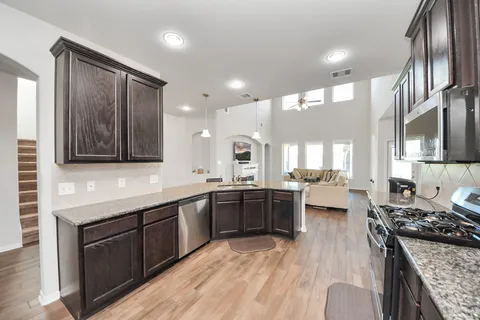 a kitchen with stainless steel appliances granite countertop a sink stove microwave and refrigerator