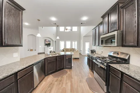 a kitchen with stainless steel appliances granite countertop a sink refrigerator and cabinets