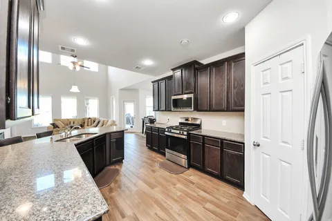 a large kitchen with stainless steel appliances granite countertop a lot of counter space and a wooden floors