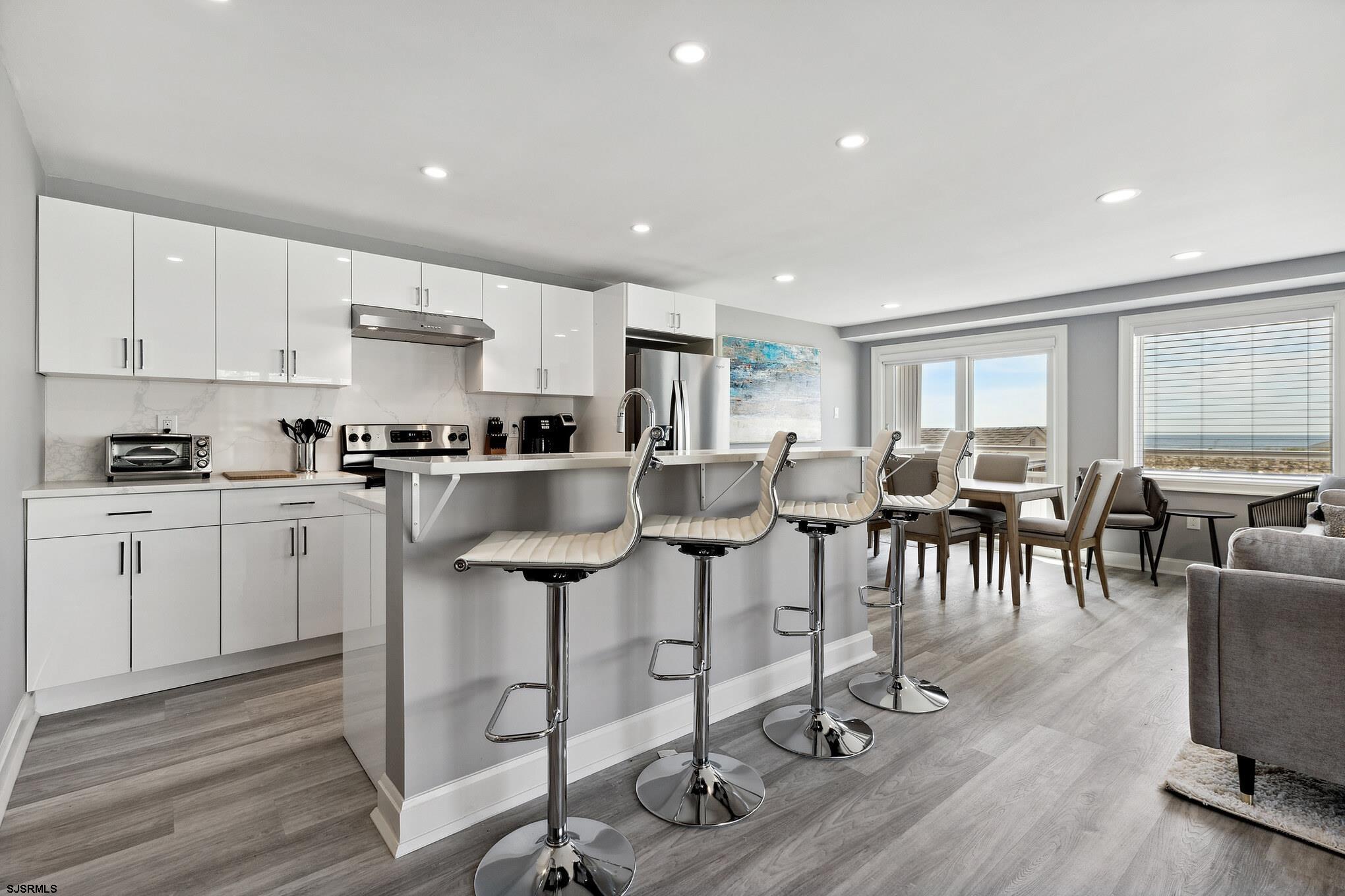 111 South Decatur Avenue Margate City, NJ 08402 - Photo 8 of 39 a kitchen with stainless steel appliances granite countertop a stove top oven a sink a dining table and chairs with wooden floor