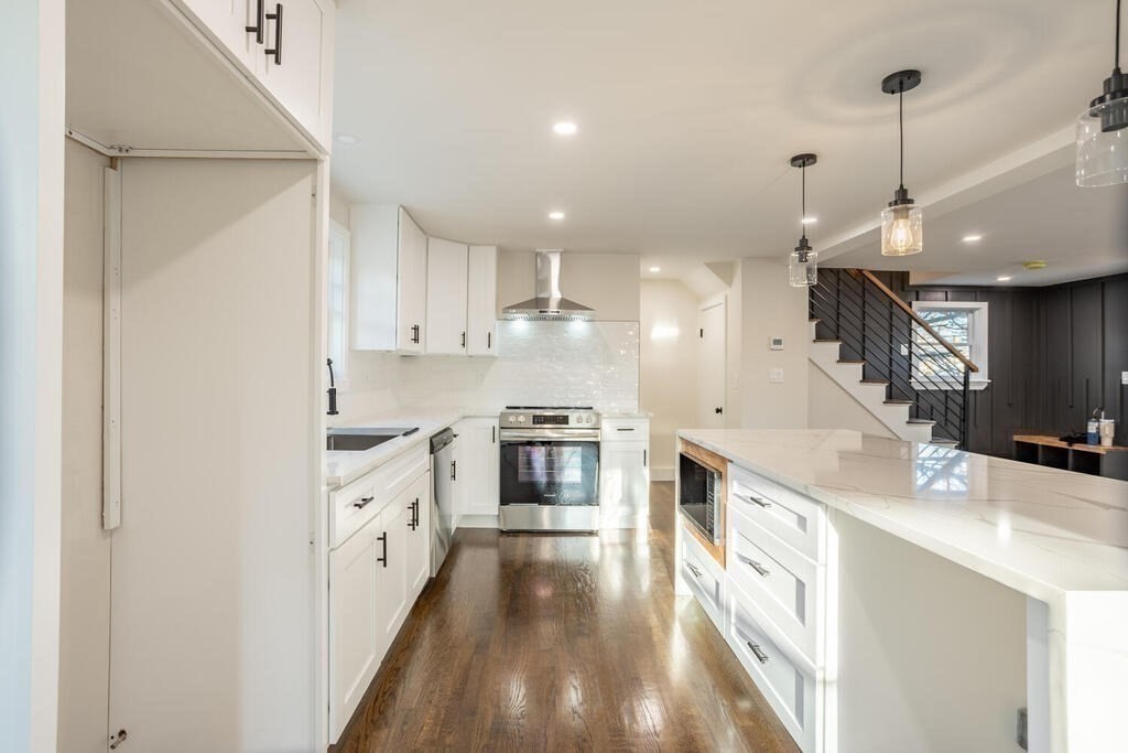 a large kitchen with stainless steel appliances kitchen island granite countertop a sink and a stove