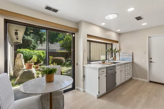 a kitchen with stainless steel appliances granite countertop a stove a refrigerator a sink with a dining table and chairs