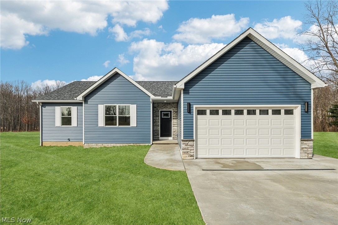 6535 North Ridge Road West Geneva, OH 44041 - Photo 1 of 48 Single story home with a front lawn, concrete driveway, an attached garage, stone siding, and roof with shingles